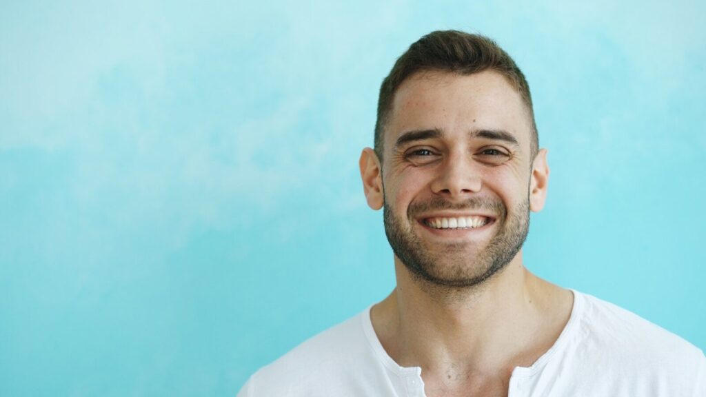 A smiling man in a white shirt against blue background